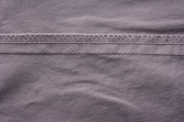 Close-up of the wrong side of a cotton shirt showing overlock and straight stitch seams with visible threads and fine fabric texture.