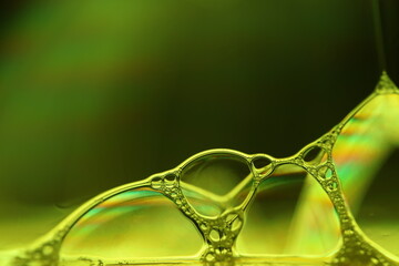 Yellow liquid surface, phenomenal structure, green oils on a dark background, colourful abstract, surrealistic art, iridescent effect