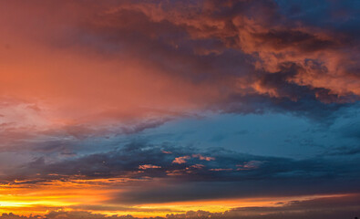 Dreamlike sunset sky filled with glowing colors above calm, layered clouds