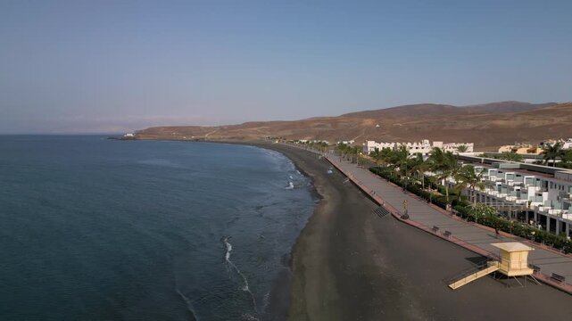 Aerial view of resorts and promenade in Tarajalejo, town situated on the slopes of volcanic coast of the southern part of the Fuerteventura Island, Canary Islands, Spain.