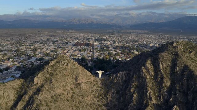 The Cristo del Portezuelo statue stands between rocky ridges, welcoming visitors at the edge of Chilecito with mountains beyond.