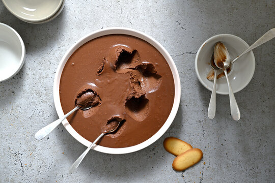 plat de pr&eacute;sentation d'une cr&egrave;me au chocolat partiellement mang&eacute;e avec des petites cuill&egrave;res
