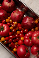 Pomegranate and assortment of red and yellow cherry tomatoes on a light marble surface