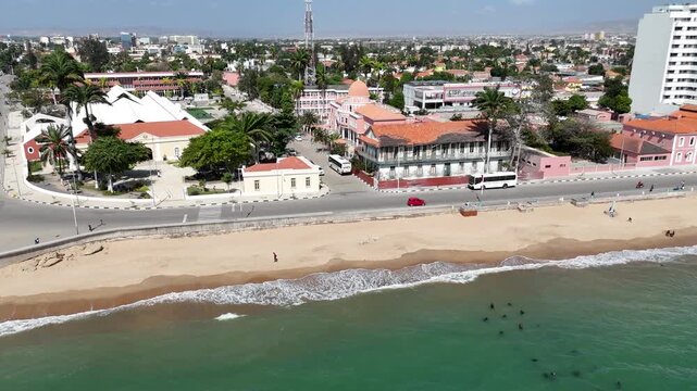 Aerial view of Benguela, Angola, showing coastal neighborhood with sandy beach, ocean waves, and colorful seaside buildings in tropical sunlight