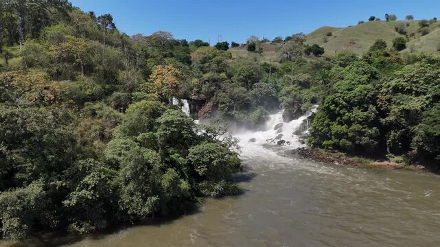 Aerial footage of Binga Falls viewed from downstream, showing the tropical river winding through green jungle toward the roaring waterfalls of Angola