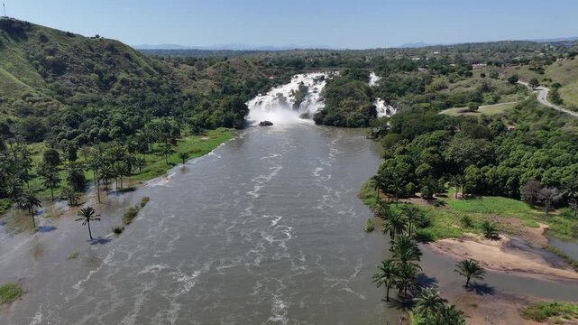 wide angle Aerial drone footage approaching Binga Falls along the Kwanza River, revealing the waterfalls framed by green hills and untouched African wilderness