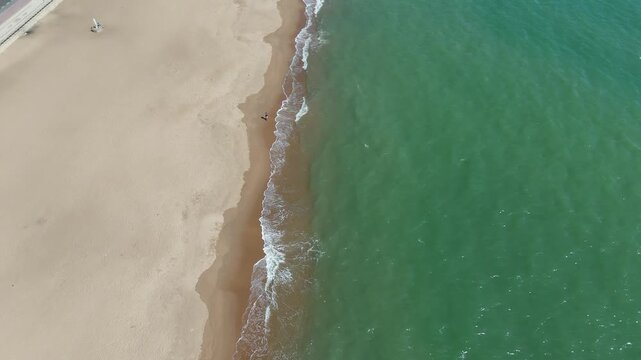 Aerial footage of Benguela beach, Angola, showing pristine turquoise waves washing onto empty golden sand in a peaceful tropical coastal setting