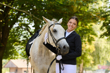 Obraz premium Young woman with her white horse outdoors, equestrian lifestyle, smiling girl and her beautiful horse in nature, friendship and love, happy moments.