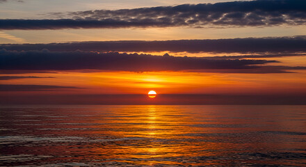 Fototapeta premium Sunset over calm sea with golden sun near horizon, tranquil beach scene