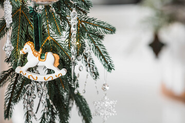 Home decoration for the New Year 2026. Symbol of the year. Horse on a spruce branch. Christmas decorations in the interior.