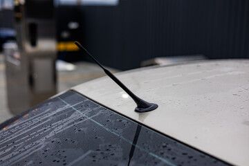 Shiny silver car with rain droplets on the headlight, captured in a close-up shot at a brightly lit car wash station
