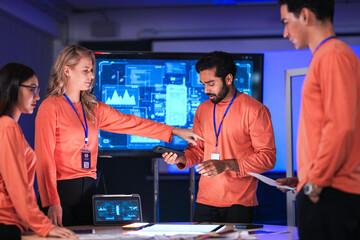 In a futuristic logistics control tower, a team manages the global supply chain, using a tablet and...