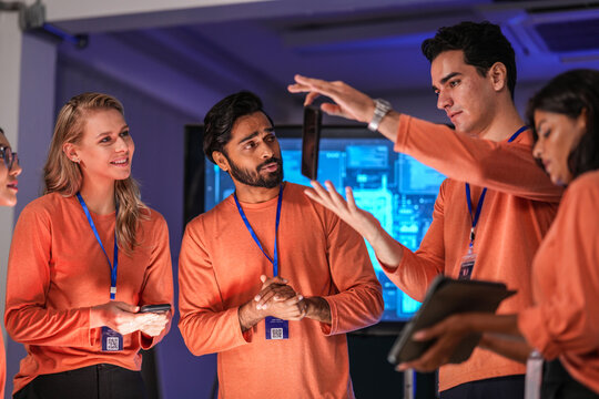 A diverse team of young innovators in a tech lab presents a new smartphone prototype, enthusiastically brainstorming its next-generation design and user interface for a future product launch. - Powered by Adobe