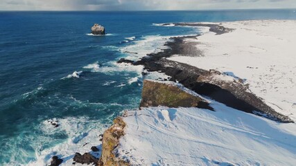 Aerial view of waves breaking on the snowy cliffs along the coast storm ocean sea on sunrise in winter - Powered by Adobe