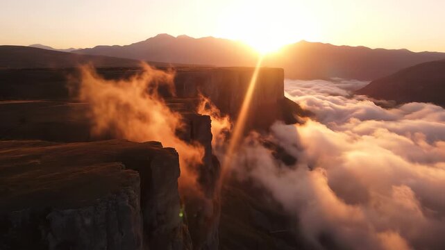 The sun rises over the dramatic cliffs, casting warm light on the misty valley below. The cliffs stand tall amidst the swirling clouds, creating a stunning natural landscape.