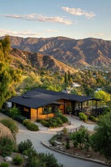 Experience the breathtaking beauty of a contemporary home, perfectly situated among lush hills that offer stunning views of a tranquil valley at sunset, all framed by a dramatic mountain backdrop