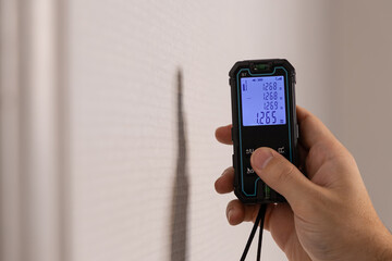 Un technicien effectuant les mesures d'une pièce d'un appartement avec un télémètre laser.