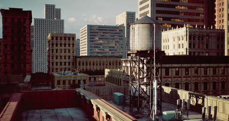 Rooftops of city buildings display diverse architectural styles and a prominent water tower, capturing a moment of urban life in the daylight hours against a clear sky.