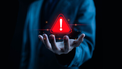 A glowing red warning alert icon floating above a businessman’s hand, symbolizing risk...