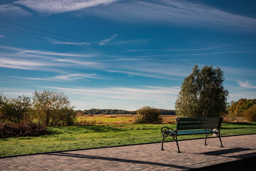 Historic narrow-gauge railway station platform with a traditional brick and timber-framed building. A person stands waiting, next to the tracks under a clear blue sky.
