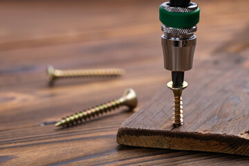 screwing a screw into wooden surface with the screwdriver. DIY concept