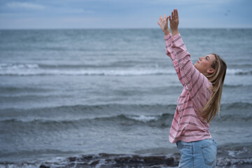 Woman reaching arms up on ocean beach
