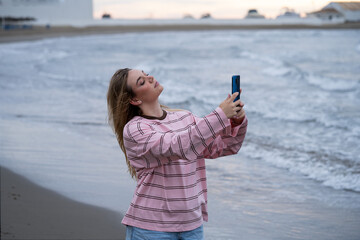 Young woman taking selfie with smartphone on beach