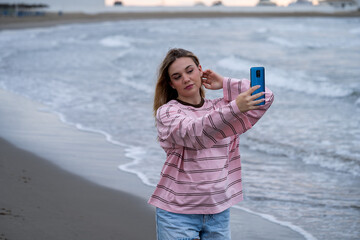Young woman taking selfie on beach at sunset