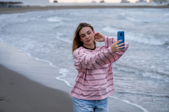 Young woman taking selfie on beach at sunset