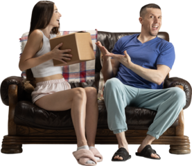 Excited couple sitting on sofa unboxing package with joyful emotions on transparent background. Concept of e-commerce visuals, delivery services, lifestyle advertising and positive home experiences.