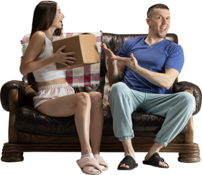 Excited couple sitting on sofa unboxing package with joyful emotions on transparent background. Concept of e-commerce visuals, delivery services, lifestyle advertising and positive home experiences.