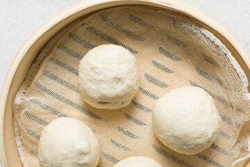 Overhead view of steamed bun in a steamer basket, top view of mantou in a bamboo steamer