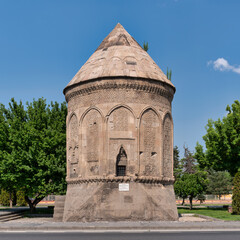 Historic Doner Kumbet, or Doner Tomb, a Seljuk mausoleum with ornate stone carvings and conical roof, against a clear blue sky in Kayseri, Turkey.