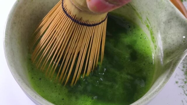 Process making matcha green tea. Mixing matcha tea with whisk in wooden bowl. Healthy matcha drinks