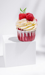 Delicious raspberry cupcake with cream frosting on a white pedestal