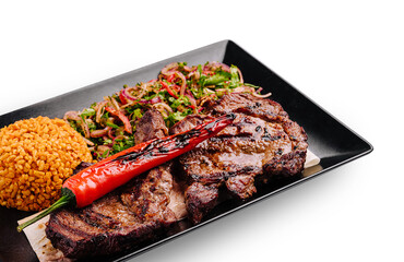 Grilled steak with rice and vegetables served on a black plate