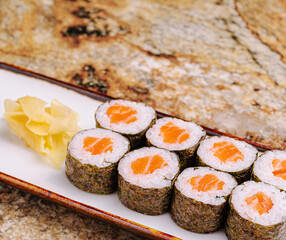 Fresh sushi rolls served with pickled ginger on a rustic countertop