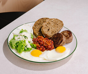Breakfast plate featuring eggs, sausage, beans, and salad on a table