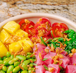 Fresh tuna poke bowl with colorful ingredients on stone countertop