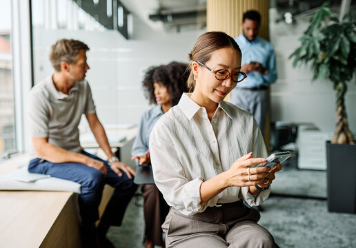 Portrait of a group of young business people having a meeting in the office. Teamwork and success concept, portrait of a smart young businesswoman using a smartphone phone and texting