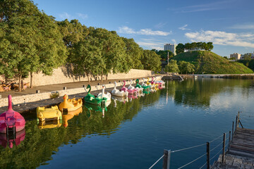 In Valencia's serene autumn, vibrant paddle boats reflect on the calm waters, inviting a peaceful day of exploration and joy.