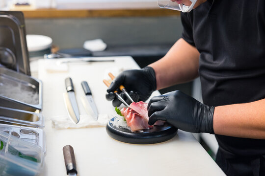 Japanese chef slicing fresh sashimi in restaurant kitchen