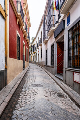 Old typical narrow street in Cordoba with old buildings with white walls decorated with colorful flower pots