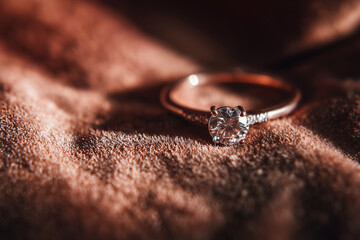 Pierścionek zaręczynowy położony na eleganckim materiale w miękkim świetle