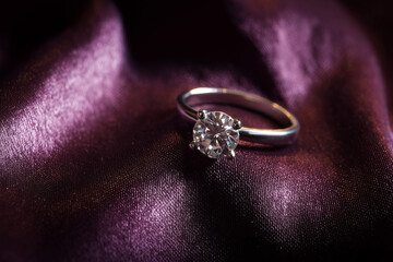 Pierścionek zaręczynowy położony na eleganckim materiale w miękkim świetle