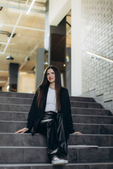Naklejka premium Woman Sitting on Stairs in a Modern Interior Setting