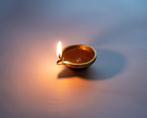 Lit Brass Diya Oil Lamp with a Bright Flame on a Softly Lit Surface metal