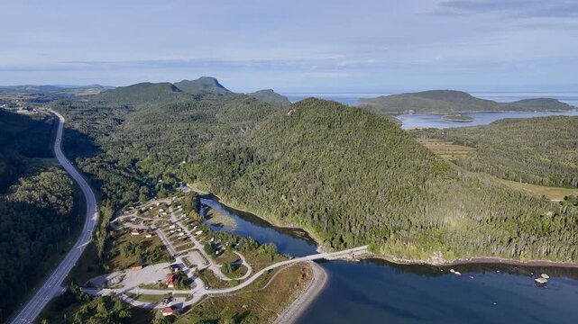 Aerial view of Bic National Park coastline, forest, campground and calm bay under blue sky. g.