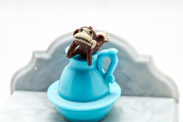 A toy monkey on top of a toy pot display
