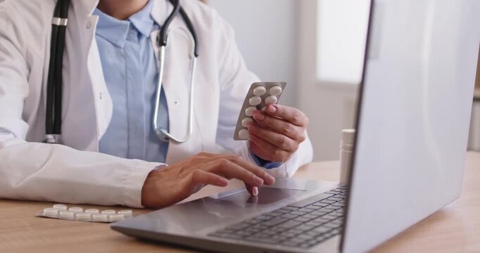 Doctor searches online medicine instruction and dosage. With pills by a laptop, clinician does search for prescription details and side effects on medical sites. Clear guide for safe care.